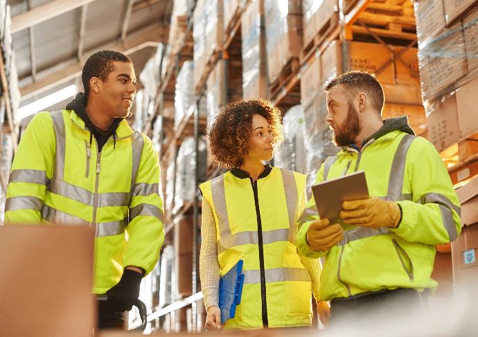 Trois employés d'usine travaillent avec un logiciel WMS